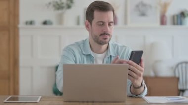 Casual Man using Smartphone while using Laptop 