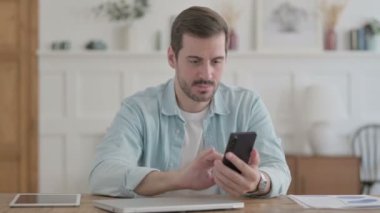 Upset Casual Man Reacting to Loss on Smartphone in Office 
