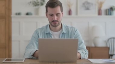 Casual Man Shaking Head in Approval While using Laptop