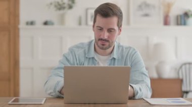 Dizüstü bilgisayar kullanırken Kayıplara Tepki Veren Sıradan Genç Adam 