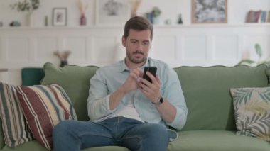 Casual Man having Success on Smartphone at home