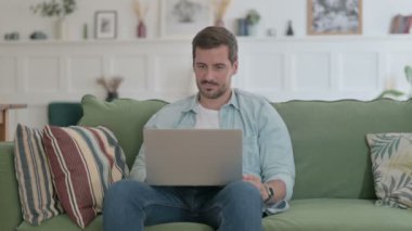 Casual Man with Laptop Reacting to Loss on Sofa 