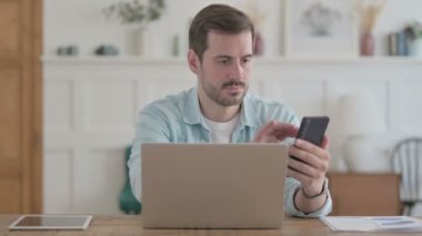 Casual Man using Smartphone while using Laptop 
