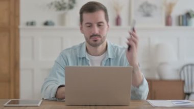 Casual Man Talking on Phone while using Laptop