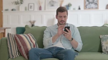 Casual Man using Smartphone on Sofa 