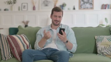 Casual Man having Loss on Smartphone at Home 