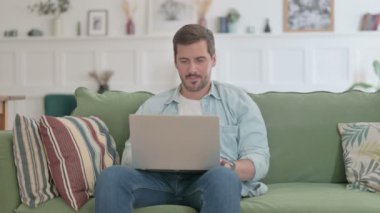 Casual Man with Laptop having Wrist Pain on Sofa 