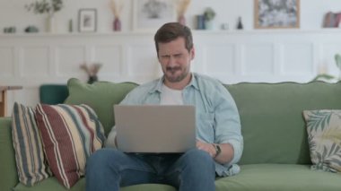 Casual Man with Laptop having Headache on Sofa 