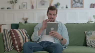 Casual Man having Loss on Tablet on Sofa 