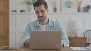 Casual Man Shaking Head in Approval While using Laptop