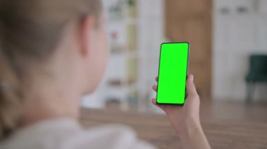 Rear View of Young Woman Looking at Smartphone with Green Chroma Screen 