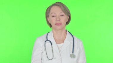 Senior Female Doctor in Denial on Green Background 