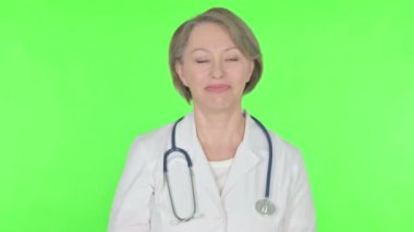 Senior Female Doctor Talking on Online Video Call on Green Background 