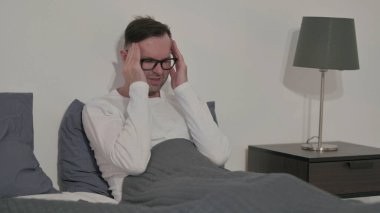 Middle Aged Man having Headache while Sitting in Bed
