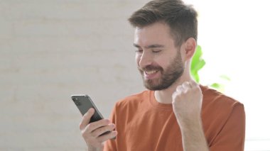 Akıllı telefonda Başarı Kutlaması Yaratıcı Genç Adam