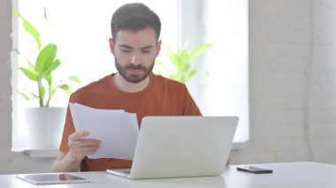 Paperwork by Creative Young Man while Using Laptop