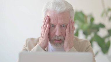Close Up of Senior Old Man Reacting to Loss While using Laptop