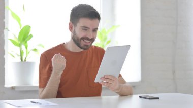 Successful Creative Young Man Celebrating on Tablet in Office
