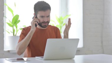 Angry Man Talking on Phone at Work