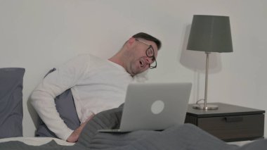 Middle Aged Man having Back Pain while using Laptop in Bed