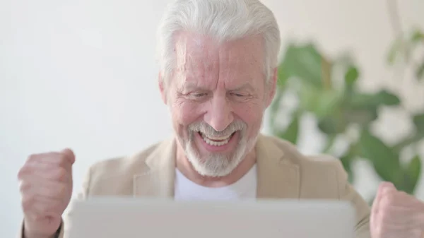 Close Up of Senior Old Man Celebrating Success while using Laptop in Office