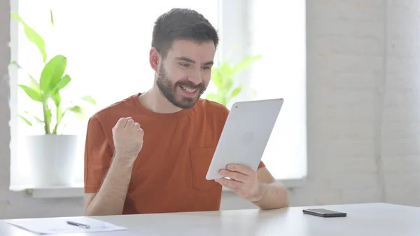Successful Creative Young Man Celebrating on Tablet in Office