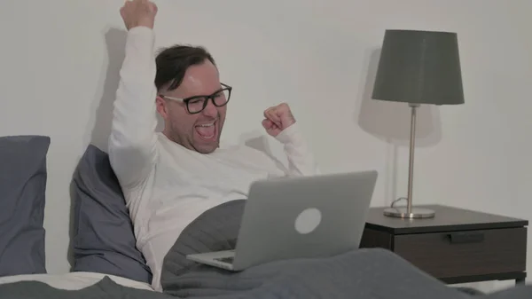 Middle Aged Man Celebrating Success on Laptop in Bed