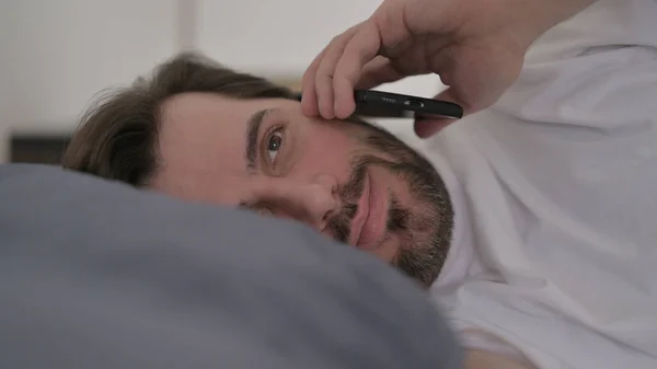Портрет Бородатого Молодого Человека Разговаривающего Вызову Смартфоне Постели — стоковое фото