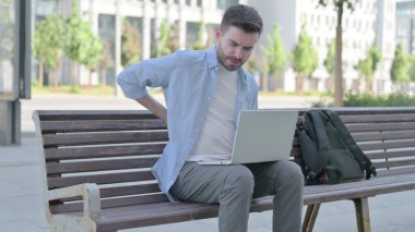 Man with Back Pain Using Laptop while Sitting on Bench