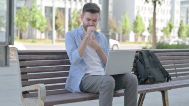 Coughing Man Using Laptop while Sitting on Bench