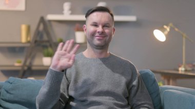 Orta yaşlı adam kameraya el sallıyor.