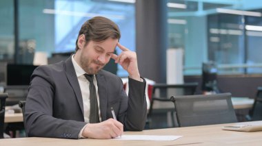 Young Businessman with Disappointment Writing on Paper