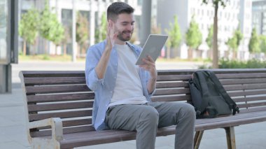 Online Video Chat on Tablet by Man Sitting on Bench
