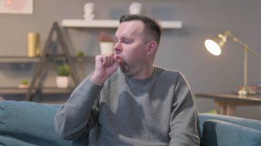 Orta yaşlı hasta adam öksürüyor.