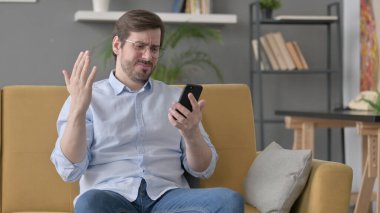 Sakallı genç adam evde akıllı telefondan kayboluyor.