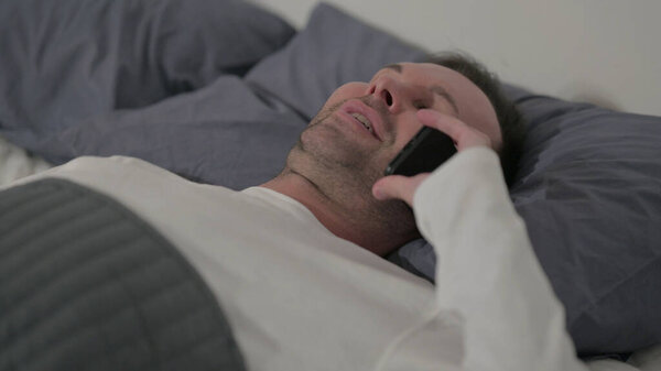 Close up Middle Aged Man Talking on Smartphone while Laying in Bed