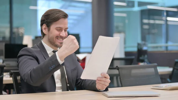 Young Businessman Celebrating Success While Reading Documents — Stockfoto