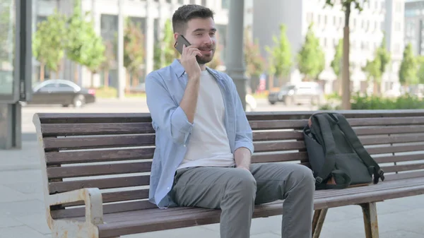 Man Talking on Phone while Sitting on Bench