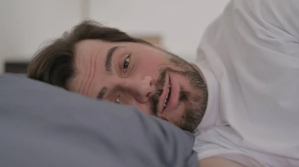 留胡子年轻人躺在床上视频通话的肖像 — 图库照片