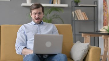 Dizüstü bilgisayarlı Sakallı Genç Adam Kanepede Kayıp 'a Tepki Veriyor