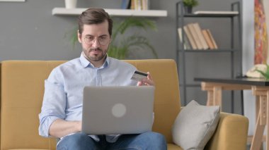 Sakallı genç adam internette ödemesini yapıyor.