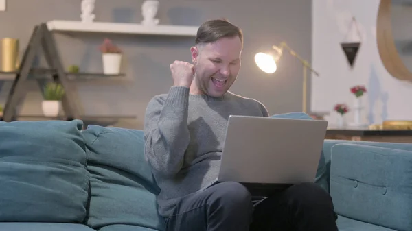 Middle Aged Man with Laptop Celebrating Success on Sofa