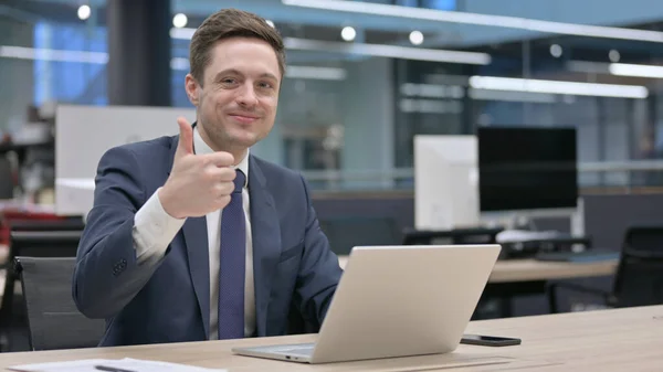 Young Businessman Showing Thumbs Sign While Using Laptop Office —  Fotos de Stock