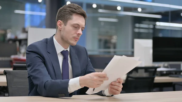 Young Businessman Reading Reports While Sitting Office — Stock Photo, Image