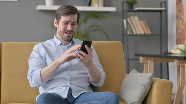 Beard Young Man Having Loss Smartphone Sitting Sofa — стоковое фото