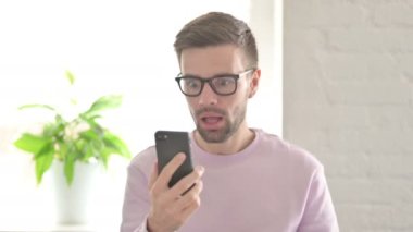 Genç Yetişkin Adam Akıllı Telefon 'da Başarı Kutlaması