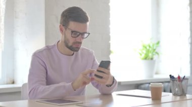 Başarılı Genç Yetişkin Adam Ofisteki Akıllı Telefonu Kutluyor 
