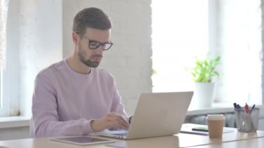 Genç Yetişkin Adam Laptop kullanırken Kameraya Bakıyor