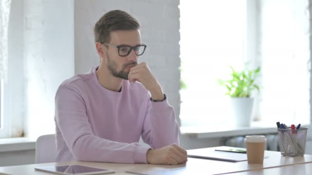 Młody Dorosły Mężczyzna Myśli Podczas Siedzenia Biurze — Wideo stockowe