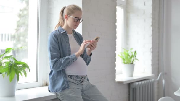 Έγκυος Όμορφη Γυναίκα Περιήγηση Στο Internet Στο Τηλέφωνο Ενώ Κάθεται — Αρχείο Βίντεο